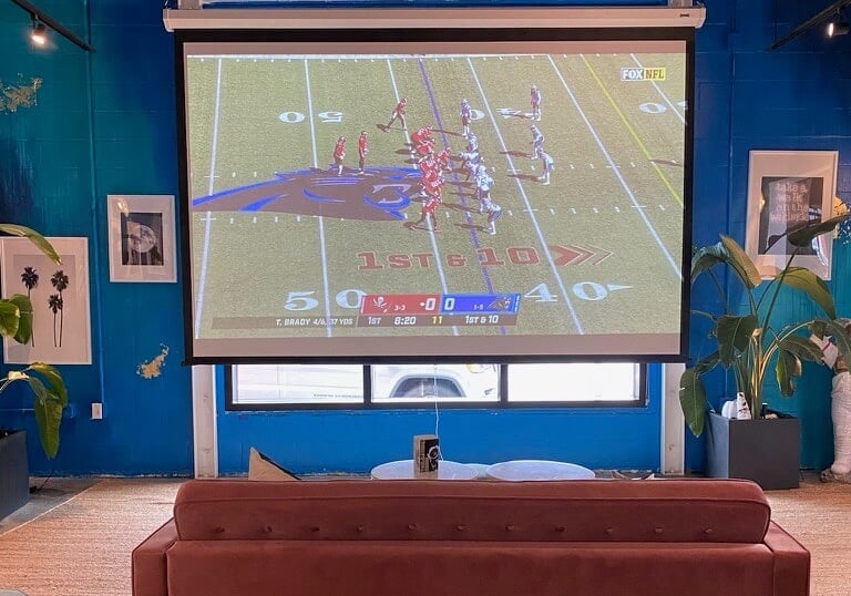 Football game being displayed on a large projector screen